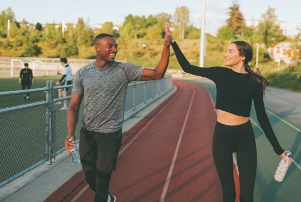 Two people on an athletics track giveing each other a high five.